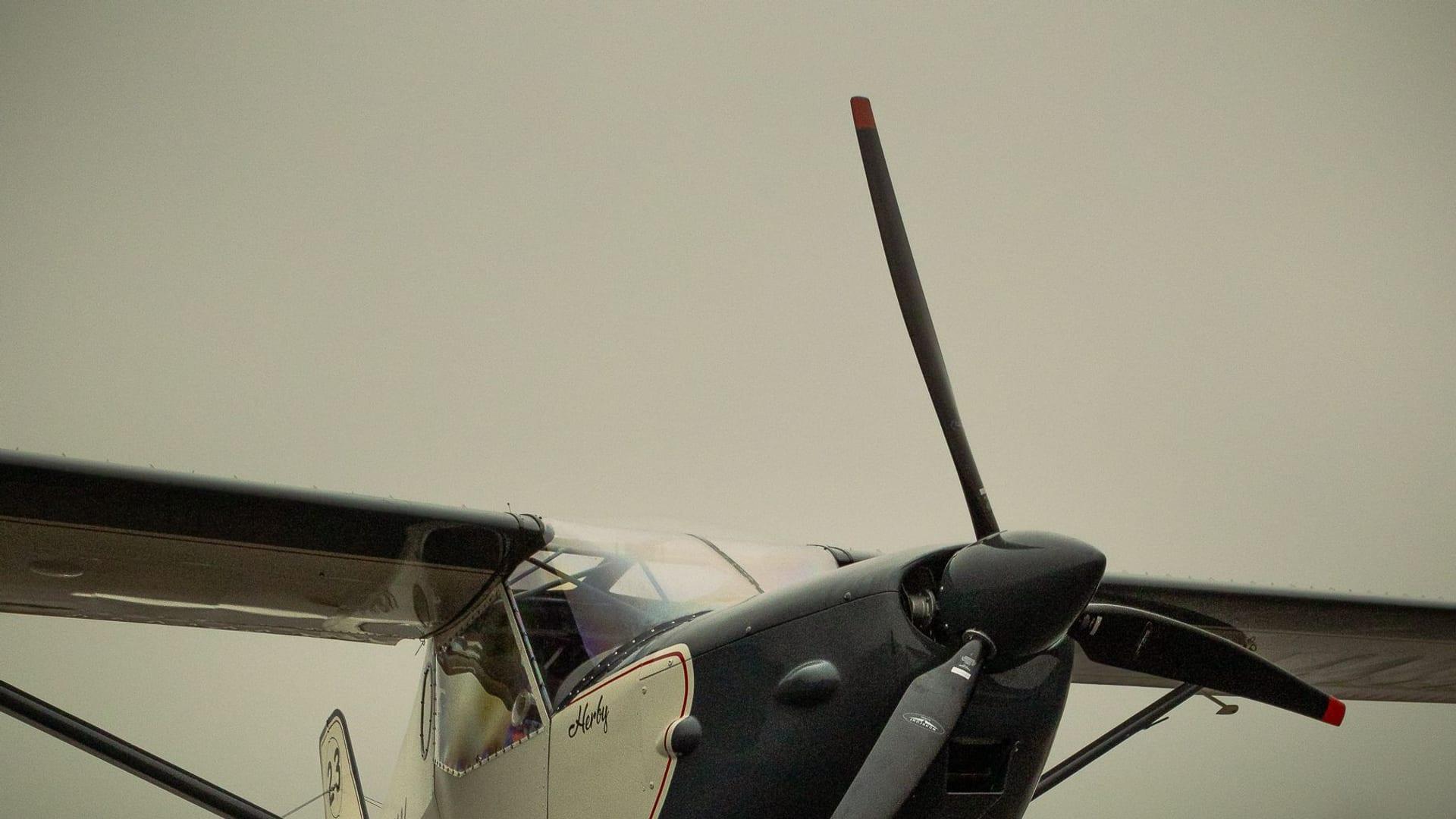 A small propeller airplane parked on a foggy runway