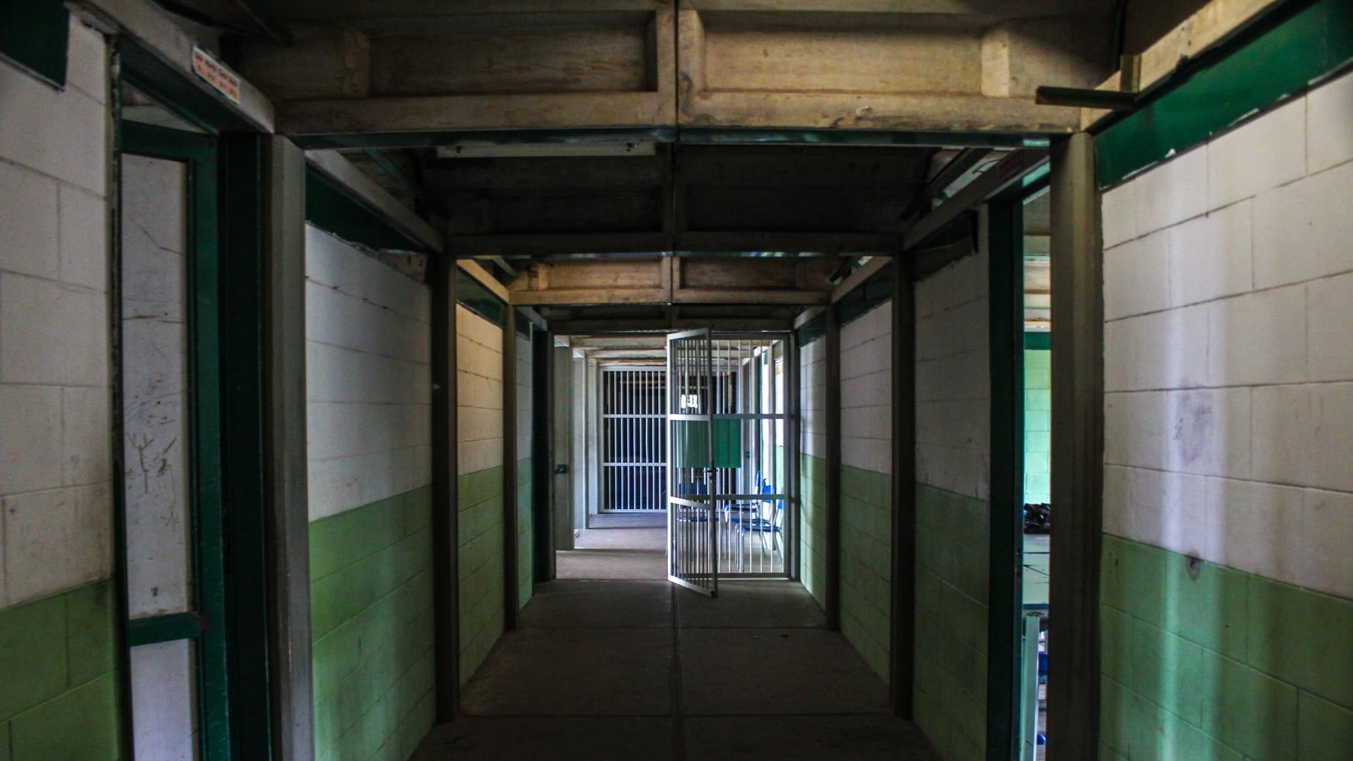 An empty prison corridor lined with cell doors