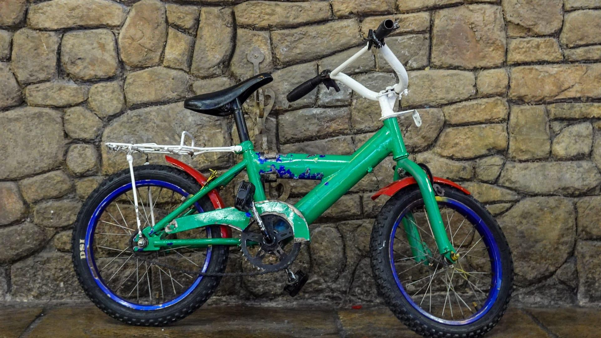 A child's bicycle leaning against a stone wall