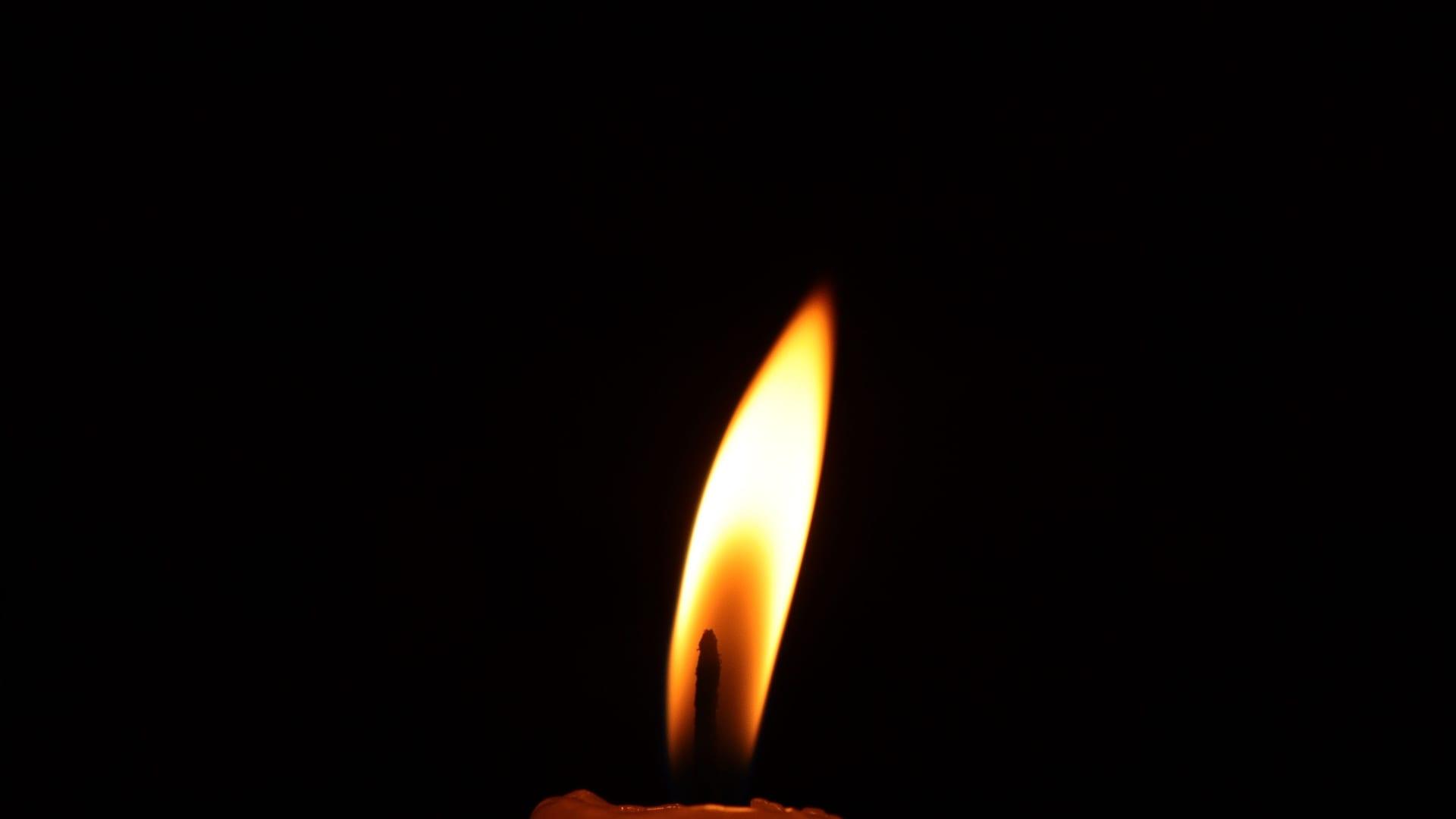 A single lit candle glowing in a dark room