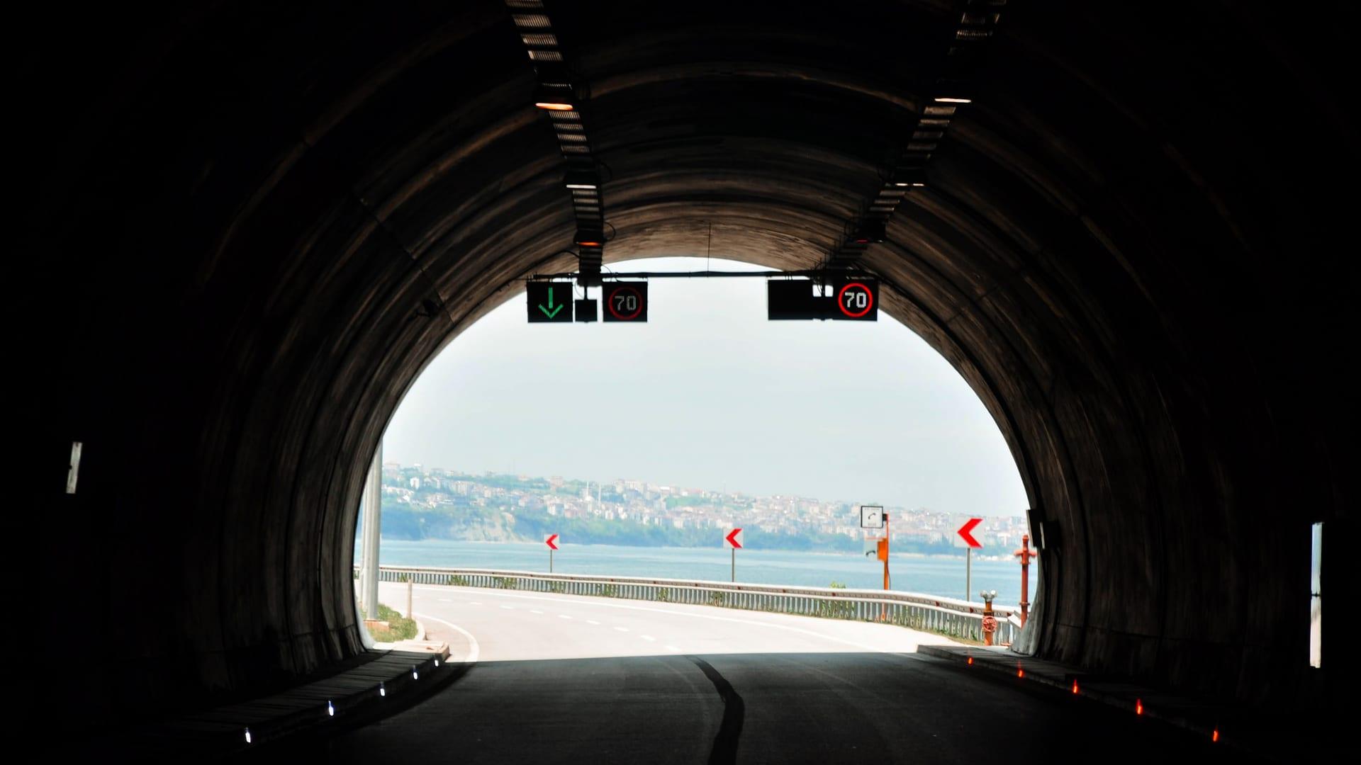 A dark tunnel opening onto a bright coastal view