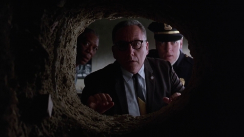 The warden and guards peer through Andy's escape tunnel